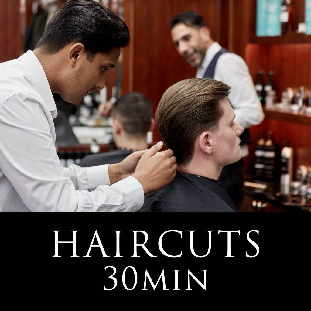 a man sitting down in a barber chair having his hair combed